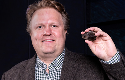 Seth Jacobson holding piece of asteroid.