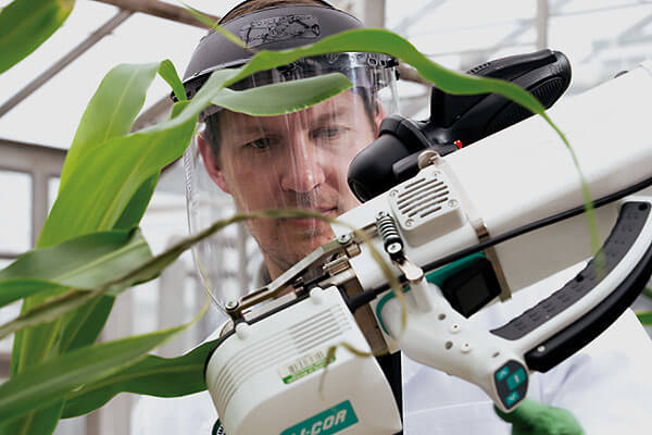 Berkley Walker working in the lab wearing a lab coat and face shield.