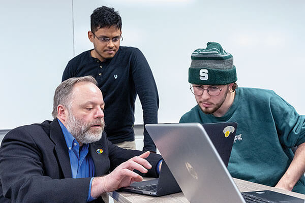 Dirk Colbry and two male students looking at a laptop.