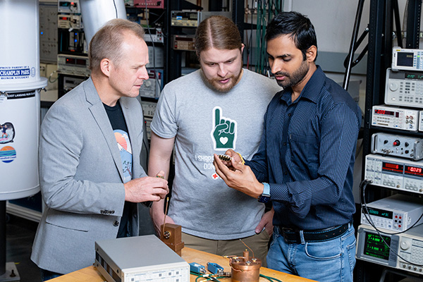 Johannes Pollanen and two male students looking at object.